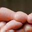 Hands gently holding a smooth, curved ceramic worry stone, symbolizing stress reduction